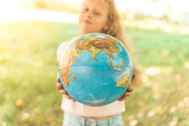 Child with earth globe portrait of a blonde european girl of elementary school with an educational g...