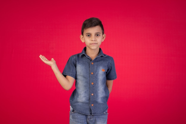 Child with facial expressions in a studio photo on red background.