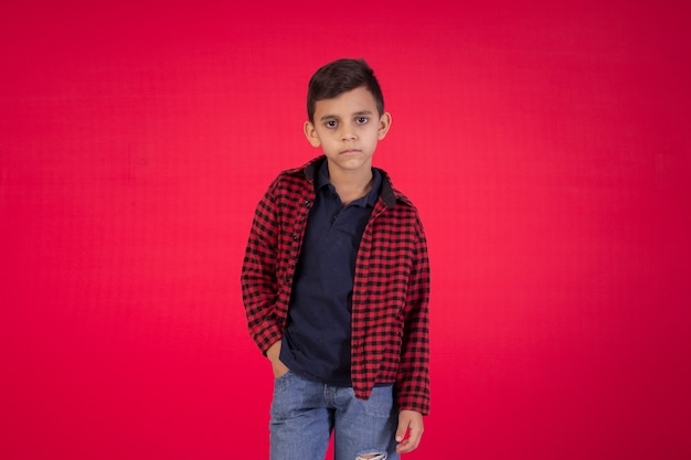 Child with facial expressions in a studio photo on red background.