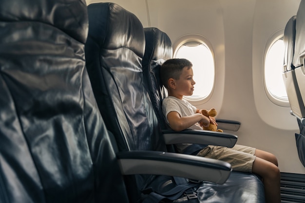 Child with favorite toy sitting on airplane seat