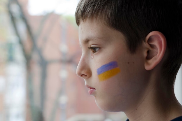 A child with the flag of Ukraine is crying Sadness longing hope Children's tears from the war