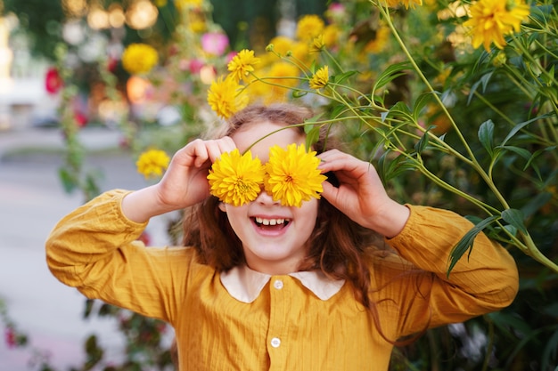 Foto bambino con gli occhi di fiori che mostrano i denti bianchi, in un'estate all'aperto.