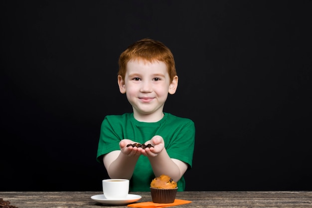 Bambino con il cibo mangiare un cupcake e giocare con il caffè