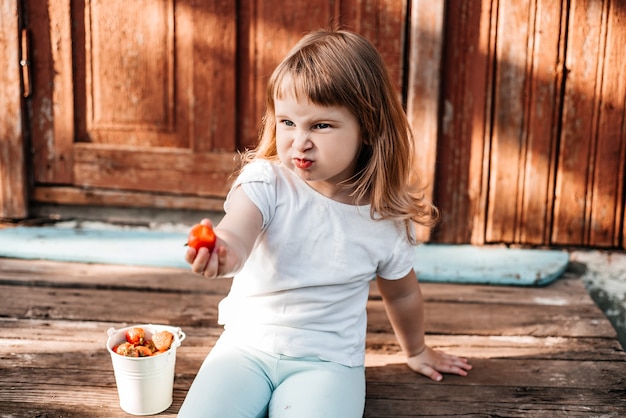 食べ物を持つ子供。いちごを健康的に食べる。