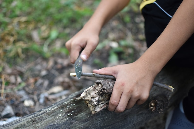 ребенок с навыками выживания в лесу. Молодой турист-путешественник с ножом