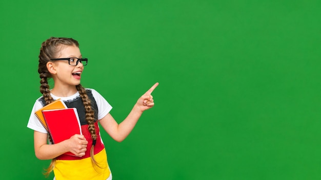 A child with a German flag points at your advertisement and holds a notebook A little girl with glasses on an isolated green background