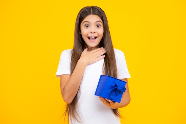 Child with gift present box on isolated studio background Gifting for kids birthday Excited teenager glad amazed and overjoyed emotions