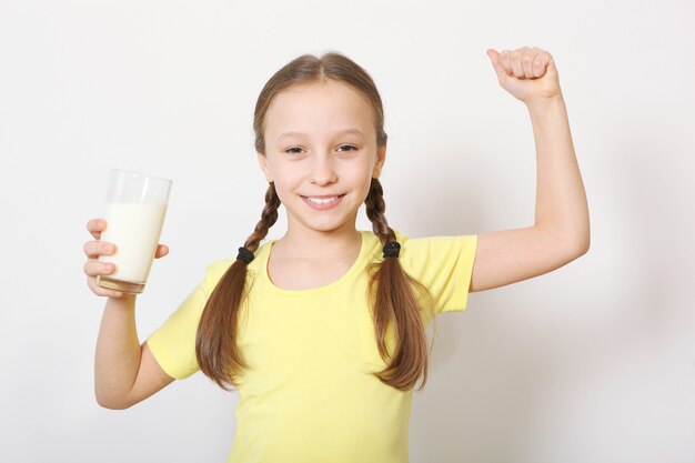 Child with glass of milk on a colored background