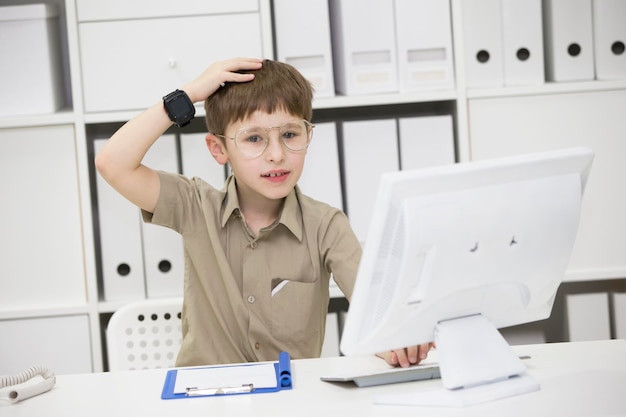 A child with glasses at the computer Schoolboy learn for the monitor An idea came to mind