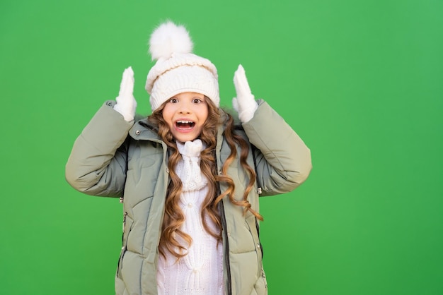 冬のジャケットと帽子で気分の良い子供。少女は冬と暖かい服を喜んでいます。寒い季節の子供服。