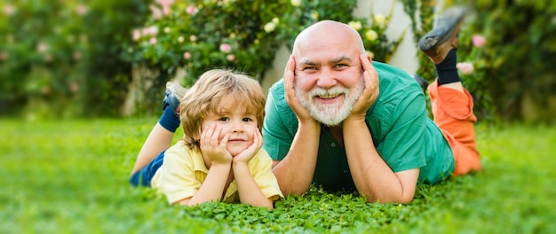 Child with Grandfather dreams in summer in nature. Portrait of happy senior and happy cute grandson. Grandfather and grandchild, spring banner.