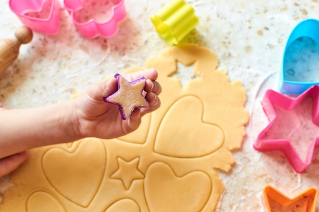 A child with his mother makes cookies, rolls out the dough and uses forms to make cookies.