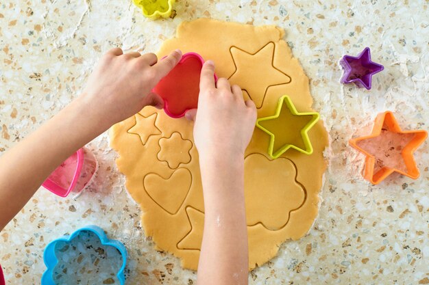 A child with his mother makes cookies, rolls out the dough and uses molds to make cookies