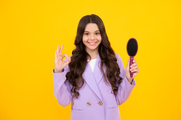 Child with long hair holding comb hairbrush for combing beauty conditioner shampoo hair beauty kids salon child hairstyle happy face positive and smiling emotions of teenager girl