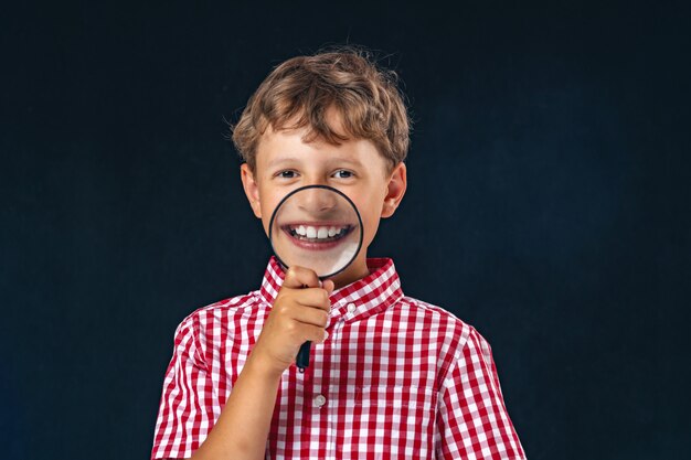 Child with magnifying glass near his mouth isolated