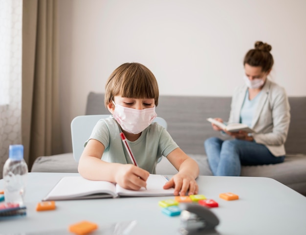 Child with medical mask being tutored at home