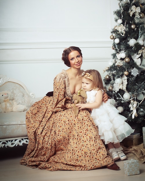 Child with mother receiving near Christmas tree.