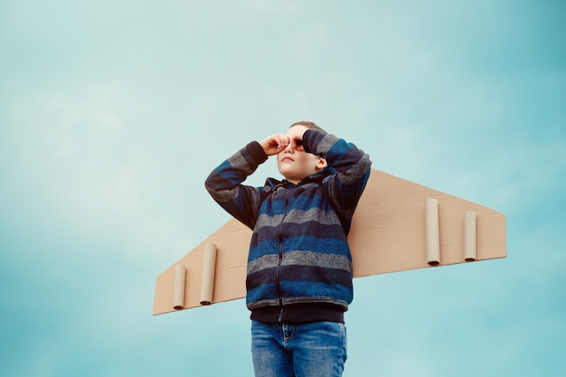 Bambino con ali di aeroplano di carta