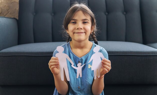 Child with a paper family in his hands.