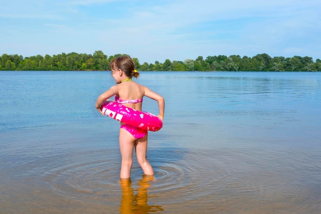 Child with a rubber ring on the beach on a sunny day the view from the back