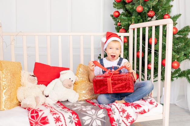 Un bambino con un cappello da babbo natale è seduto in una stanza dei bambini