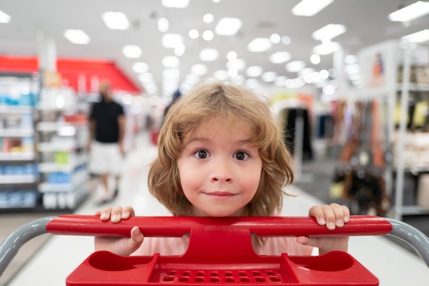 Фото Ребенок с тележкой для покупок в продуктовом магазине забавный ребенок с тележкой для покупок, покупающий еду в продуктовом магазине ...