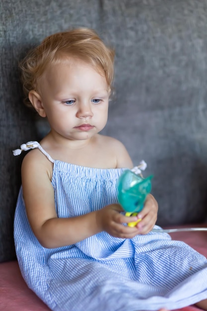 A child with snot holds a mask from a nebulizer in his hands