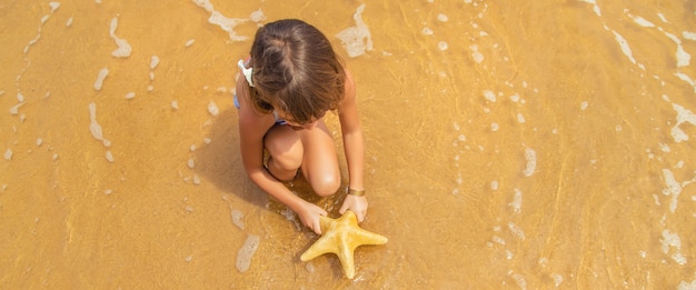 A child with a starfish in his hands on the beach