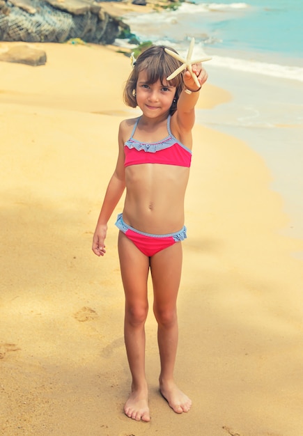 Un bambino con una stella marina in mano sulla spiaggia