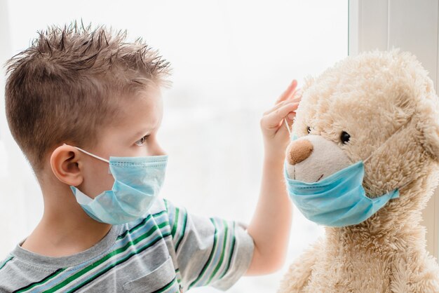 Child with a teddy bear sits in quarantine during coronavirus pandemic