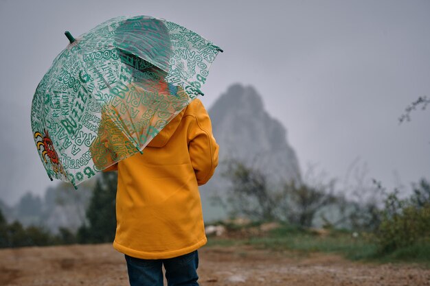 우산과 노란 재킷을 입은 아이