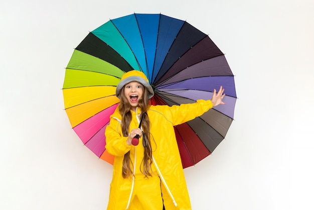 A child with an umbrella and in a yellow raincoat and panama\
hats beautiful little girl with long hair on a white isolated\
background