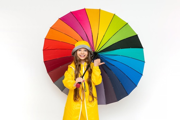 A child with an umbrella and in a yellow raincoat and panama hats Beautiful little girl with long hair on a white isolated background