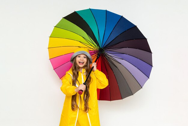 A child with an umbrella and in a yellow raincoat and panama\
hats beautiful little girl with long hair on a white isolated\
background