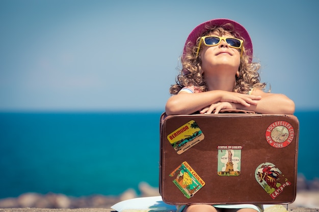 Bambino con valigia vintage in vacanza estiva concetto di viaggio e avventura