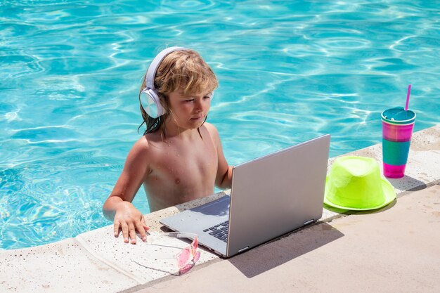 Child working with laptop on summer vacation holidays Little freelancer using computer remote working in swimming pool Summer online technology