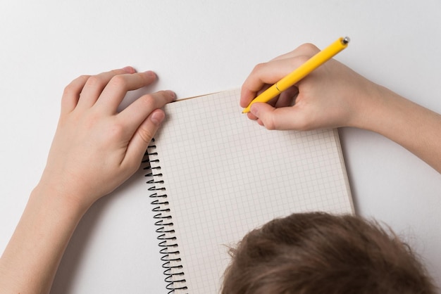 Child writes in notebook Doing homework White background Top view