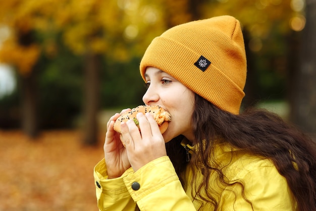 a child in yellow clothes has a burger in the fall in the park