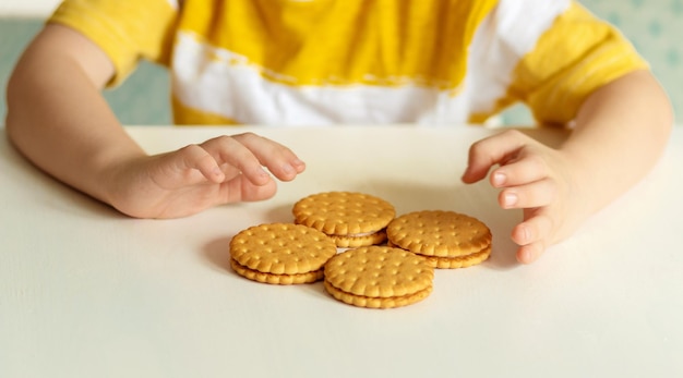 Child39s hands holding cookies in a yellow tshirt close up