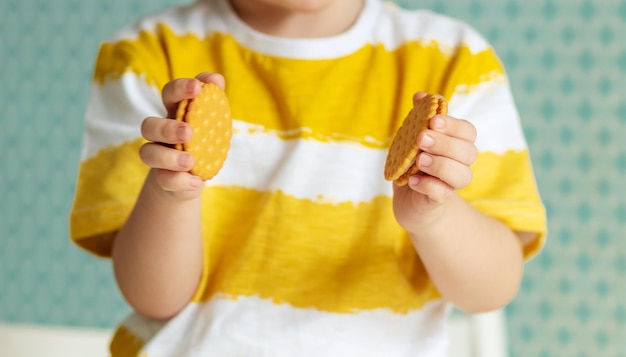 Child39s hands holding cookies in a yellow tshirt close up