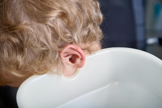 Child39s head tilted onto a water tank while rinsing the ears in the hospital