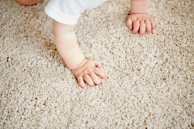 Foto concetto di infanzia, infanzia e persone - mani di bambino che strisciano sul pavimento o sul tappeto