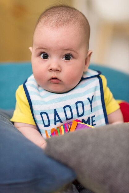 childhood, babyhood and people concept   happy little baby boy sitting between the pillows on sofa at home