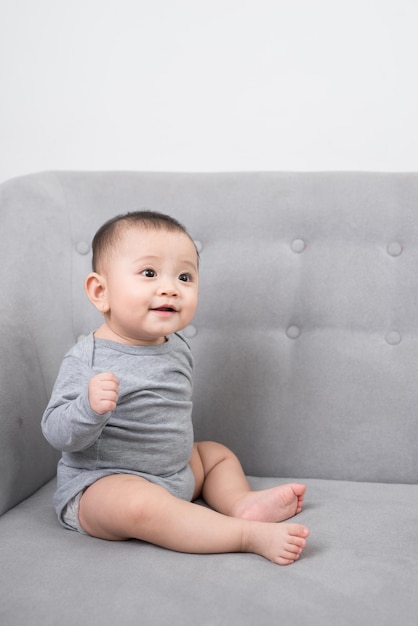 Photo childhood babyhood and people concept happy little baby girl sitting on sofa at home