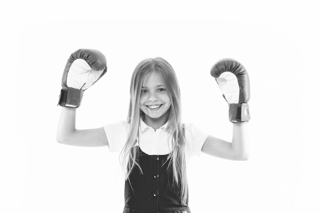 Childhood and childcare Kid athlete show power Happy child in boxing gloves isolated on white Little girl smile before training or workout Sport activity and energy