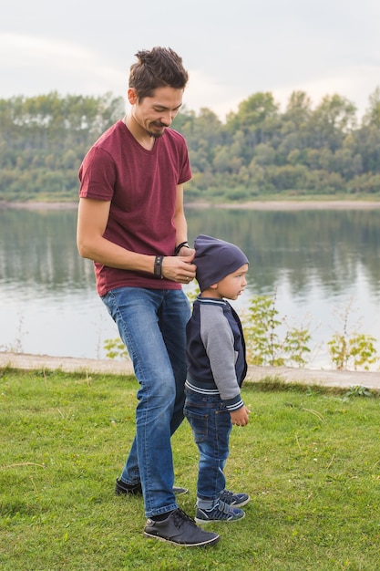 Childhood, family concept - father playing with son near the lake