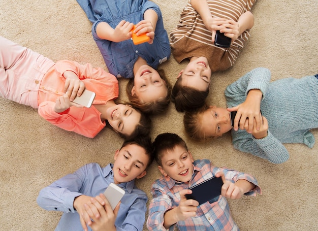 childhood, fashion, friendship and people concept - happy smiling children lying on floor in circle