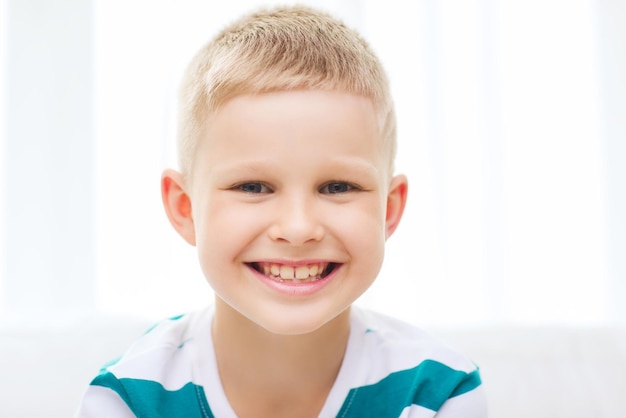 childhood, happiness, home and people concept - portrait of smiling little student boy at home