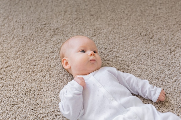 Childhood, infant and people concept - small baby lying on the floor