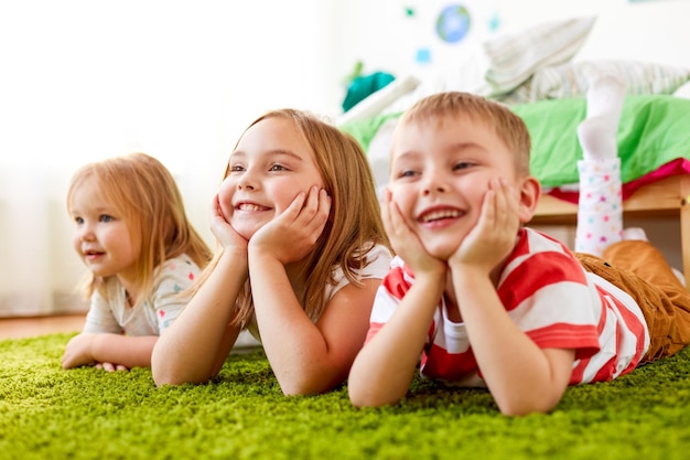 Childhood leisure and family concept happy little kids lying on floor or carpet